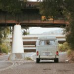 Klasyczny kamper Volkswagen jedzie boczną drogą pod wiejskim wiaduktem