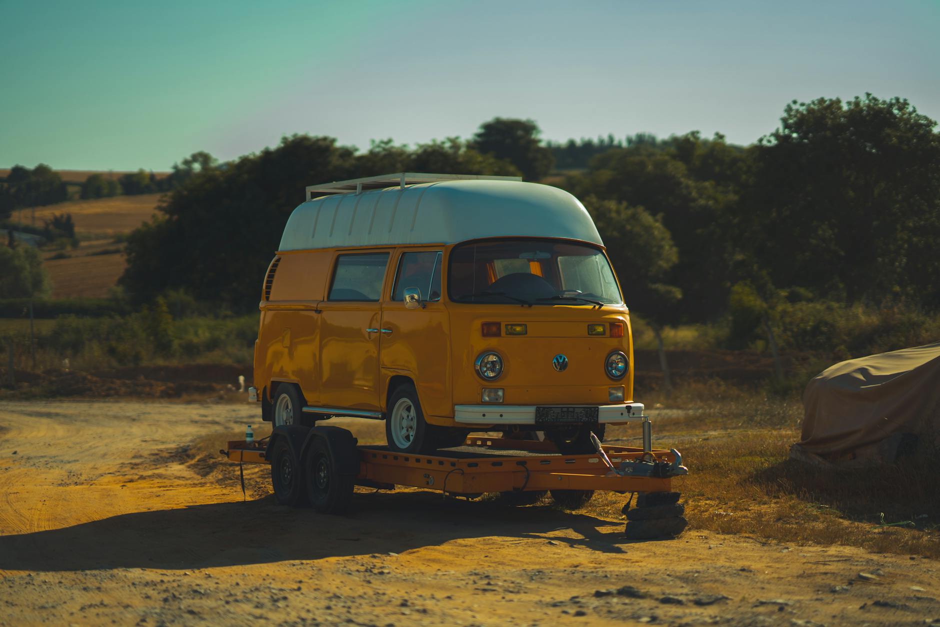 Żółty zabytkowy kamper na przyczepie na tle malowniczego krajobrazu
